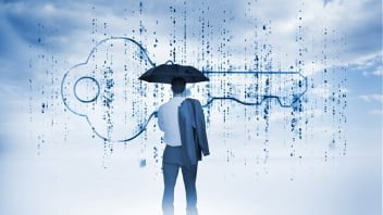 Businessman with an umbrella looking at a giant key with blue sky on the background